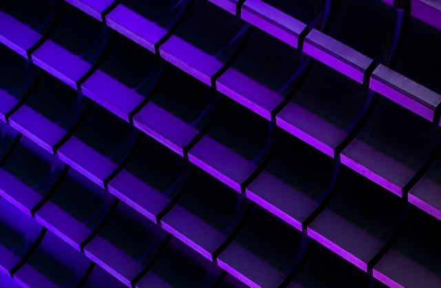 Photograph of neon purple and blue glowing bricks arranged in a 3D pattern against a dark background